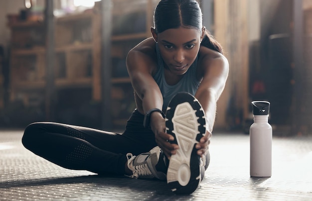 Ponerse ágil y flexible antes de comenzar su sesión. Una foto de una joven deportista estirando las piernas mientras hace ejercicio en un gimnasio.