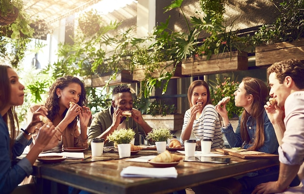 Ponerse al día con las estadísticas mientras disfruta de un buen bocado Captura recortada de un grupo de trabajadores creativos que se reúnen para almorzar en un café