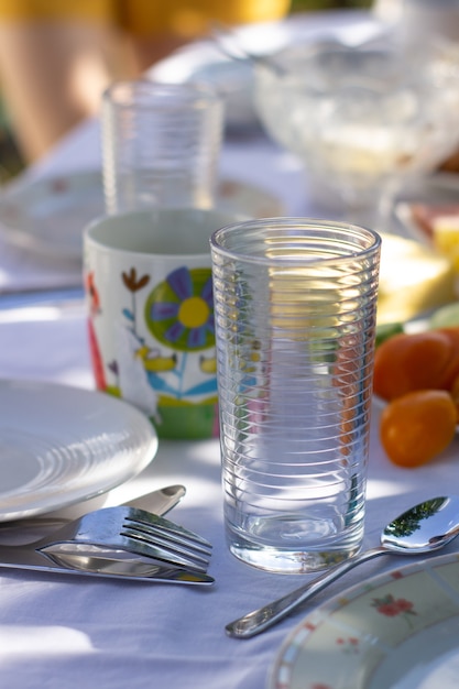 Ponha a mesa na natureza. Toalha de mesa branca. Festa casual ao ar livre na primavera ou verão no jardim preparada para o almoço e jantar.