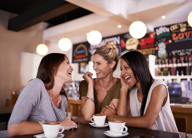 Poniéndose al día con las noticias Foto de tres amigos divirtiéndose juntos en una cafetería