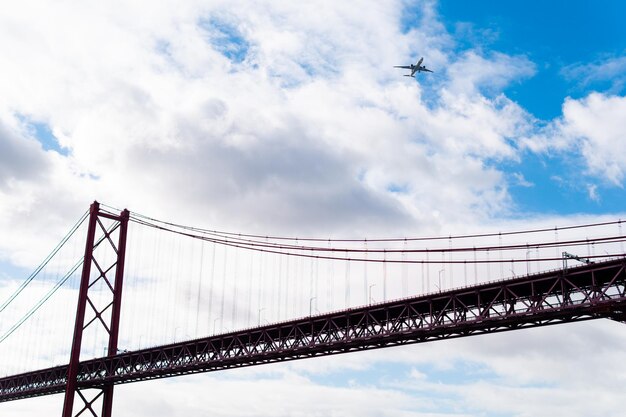 Ponte 25 de abril vista de baixo enquanto um avião passa por cima em lisboa