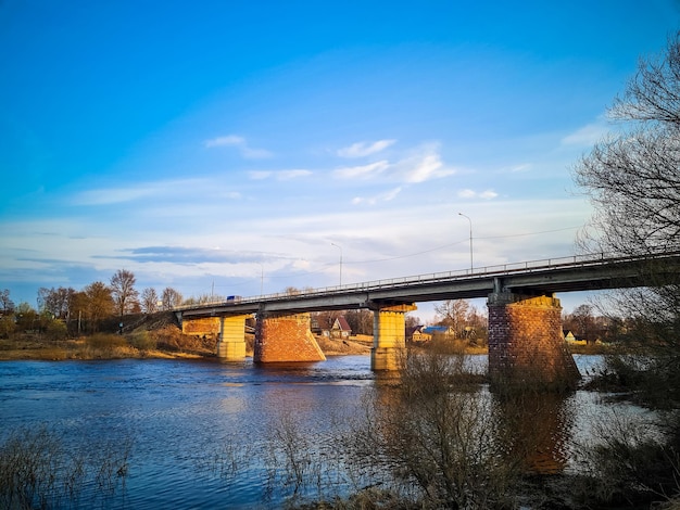 Ponte antiga sobre o rio com pilares de pedra Fluxo rápido de água na primavera Vista do pôr do sol