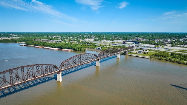 Ponte de arco de ferro aéreo sobre a água do rio Ohio, cidade distante escura, céu azul