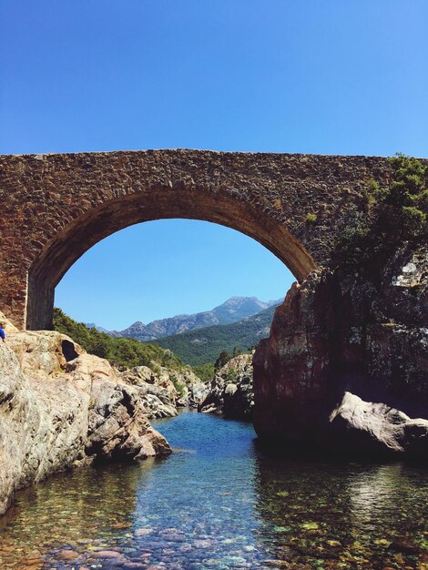 Foto ponte de arco sobre o rio contra o céu azul claro