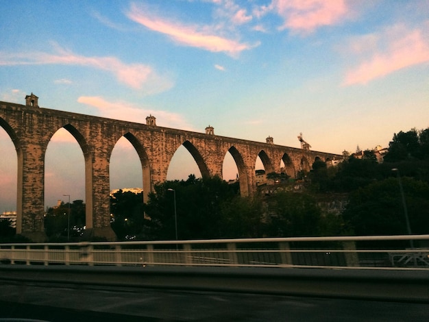 Foto ponte de arco sobre o rio contra o céu durante o pôr do sol