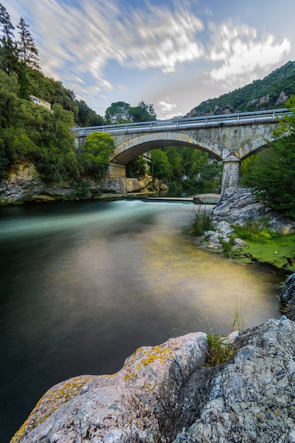 Ponte de pedra, rio colorido e nuvens