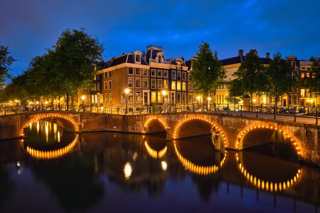 Ponte do canal de Amsterdã e casas medievais à noite