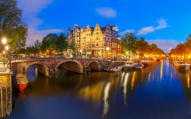Ponte do canal de Amsterdã e casas típicas, barcos e bicicletas durante a noite crepúsculo hora azul Holanda Holanda
