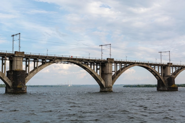 Foto ponte ferroviária alta e arqueada feita de concreto sobre o rio dnieper