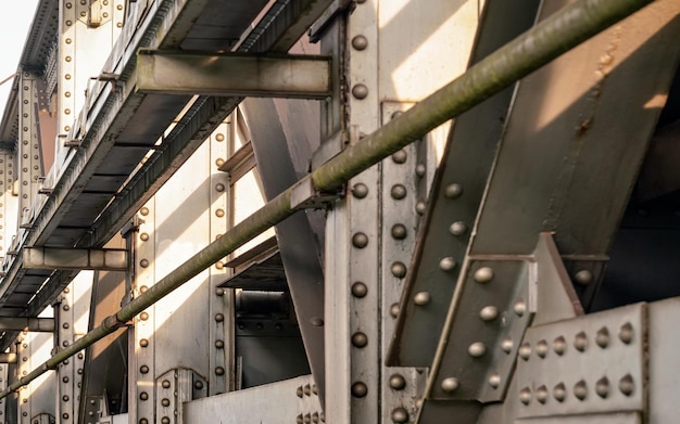 Ponte ferroviária, detalhe em chapas de aço, juntas, grandes porcas e parafusos iluminados pelo sol. fundo industrial abstrato