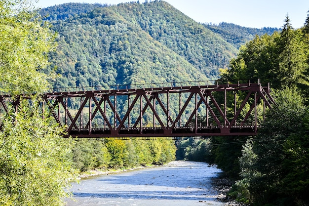 Ponte ferroviária. Túnel ferroviário com barras vermelhas enferrujadas. Ponte ferroviária abandonada. Olhando para baixo nas trilhas em uma ponte de trem