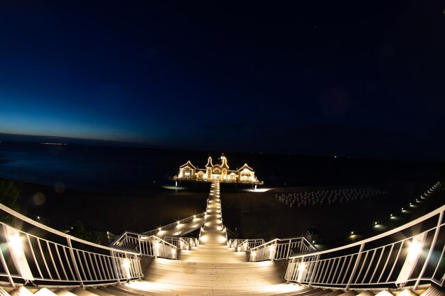 Foto ponte iluminada sobre o mar contra o céu à noite