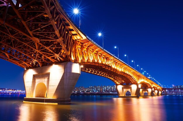 Foto ponte iluminada sobre o rio à noite