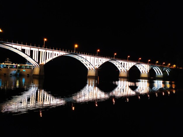 Foto ponte iluminada sobre o rio contra o céu à noite