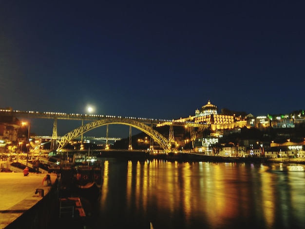 Foto ponte iluminada sobre o rio contra o céu à noite