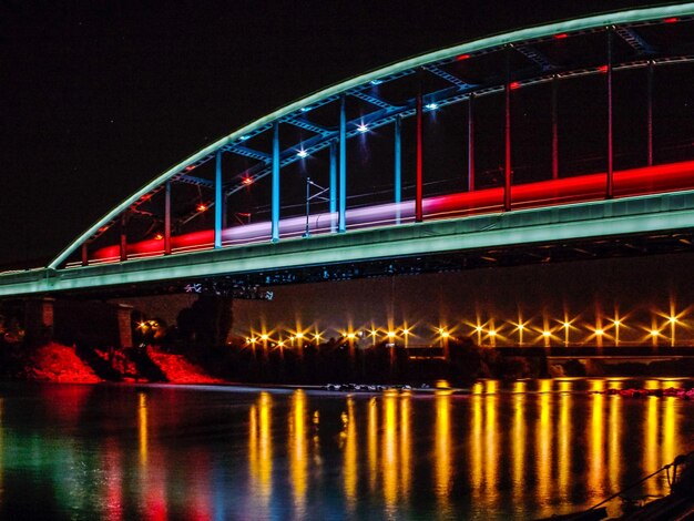 Foto ponte iluminada sobre o rio contra o céu à noite