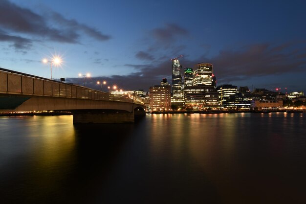 Ponte iluminada sobre o rio na cidade à noite