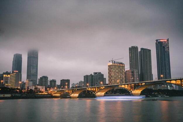 Ponte iluminada sobre o rio na cidade ao anoitecer