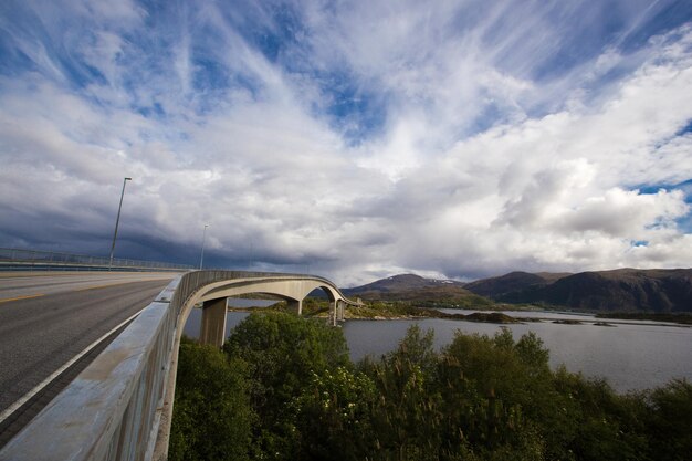 Ponte para a ilha rochosa com uma bela paisagem de nuvens ao fundo, Noruega