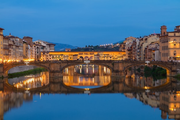 Ponte Santa Trinita-Brücke mit Reflexion im Arno-Fluss nachts, Florenz, Italien