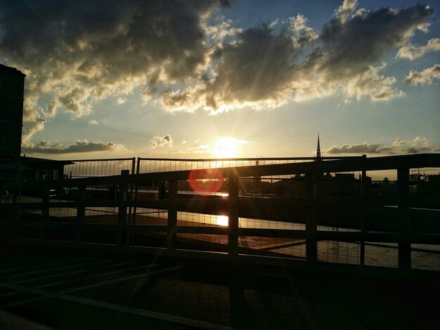 Ponte sobre o rio contra o céu nublado ao pôr-do-sol