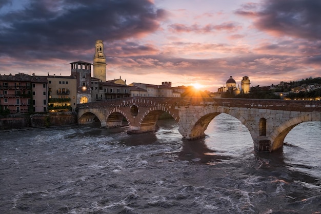 Ponte sobre o rio por edifícios contra o céu nublado durante o pôr do sol