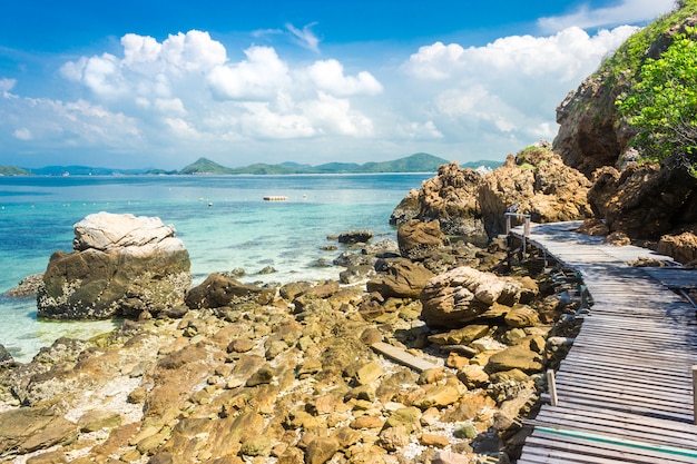 Ponte tropical da rocha e da madeira da ilha na praia com céu azul.