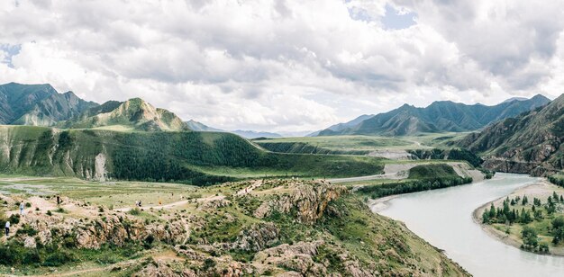 Ponto de vista com turistas contra o pano de fundo de um vale de montanha com um rio turquesa