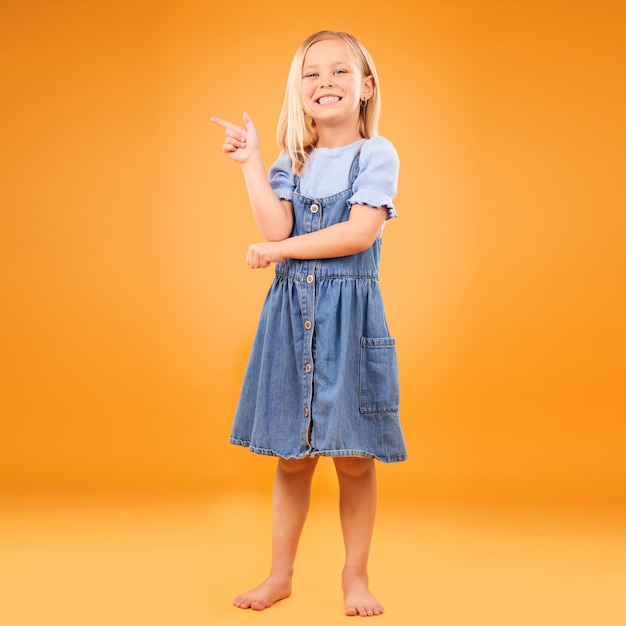 Ponto retrato feliz e criança em estúdio para anúncio publicitário ou promoção Menina descalça excitada em um fundo laranja para venda de gesto de mão ou sinal para espaço de maquete ou moda