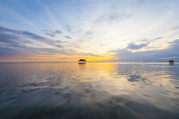 Ponton, der auf das Wasser am Sonnenunterganghintergrund schwimmt