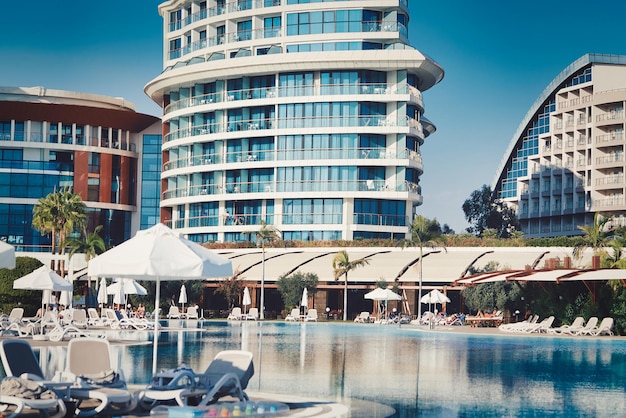 Pool mit blauen Wasserliegen und Sonnenschirmen im Hintergrund des Hotels