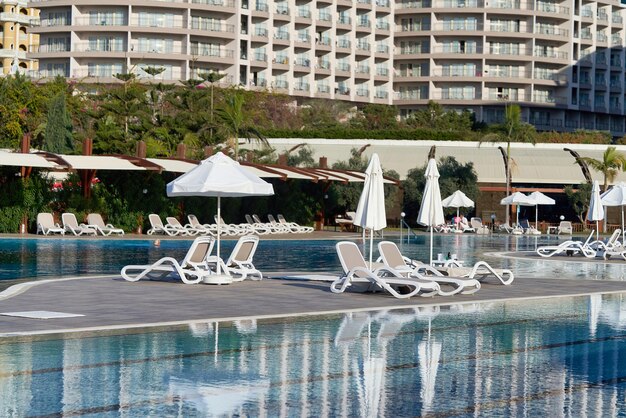 Pool mit blauen Wasserliegen und Sonnenschirmen im Hintergrund des Hotels