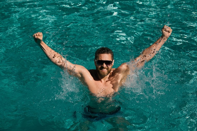 Pool resort hombre feliz en la piscina hombre de vacaciones de verano en gafas de sol relajándose en la piscina