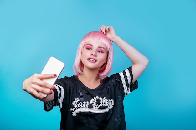Foto pop-girl-porträt mit rosa perücke und selfie