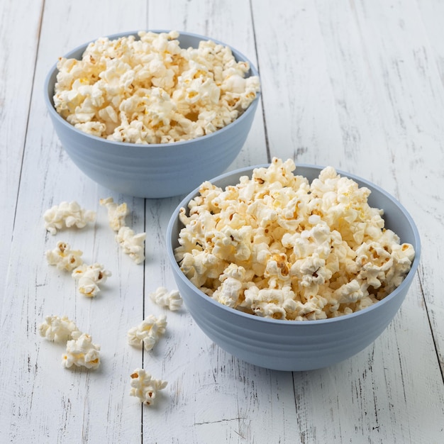 Popcorn auf einem blauen Schalen über weißem Holztisch