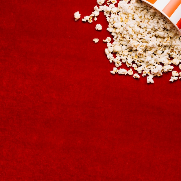 Foto popcorn derramou do balde no pano vermelho