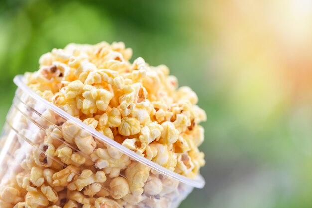 Popcorn im Cup und Naturgrün und Sonnenlicht backgroubd / süßes Butterpopcornsalz