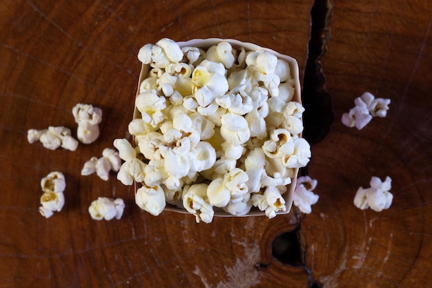 Popcorn im gestreiften Retro-Rot-Weiß-Karton für Kino auf Holztisch Nahaufnahme