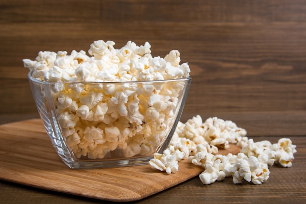 Popcorn in der Glasschüssel auf hölzernem