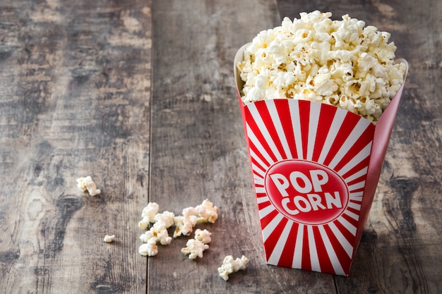 Popcorn in der Verpackung auf Holztisch gestreift