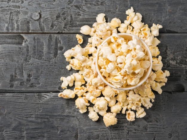 Popcorn in einem Pappbecher und auf dem Tisch