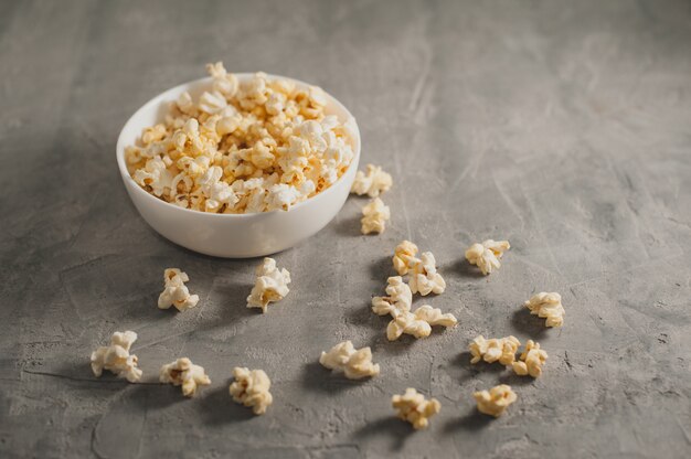 Popcorn in einer weißen Platte auf einem konkreten grauen Hintergrund