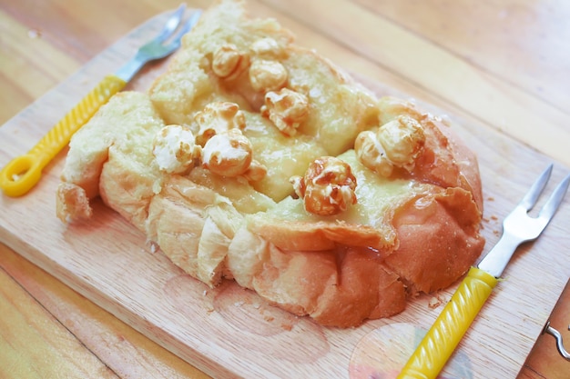 Popcorn überstieg mit Kondensmilch Toastbrot auf Holz