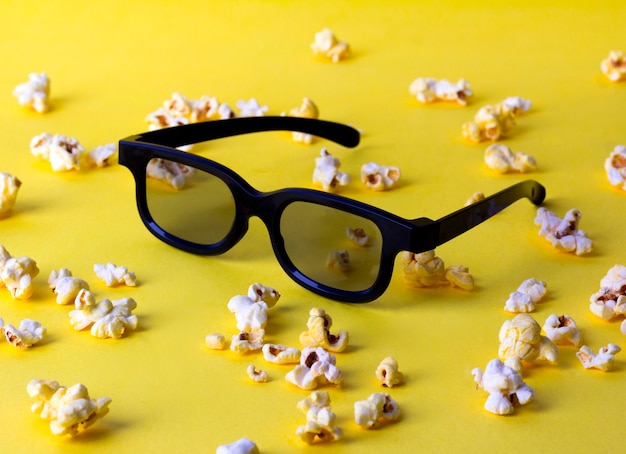 Popcorn und 3D-Gläser am gelben Tisch.