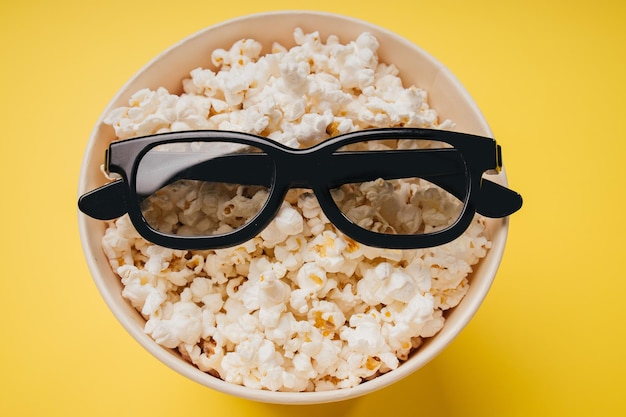 Popcorn und Brille zum Ansehen eines Films auf gelbem Hintergrund Draufsicht