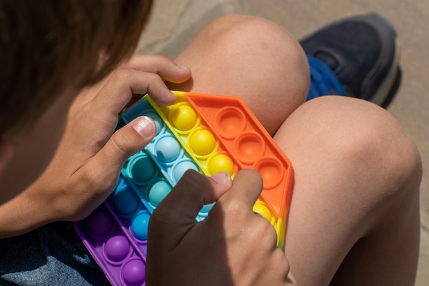 Foto popit brinquedo nas mãos de um menino brincando em close-up