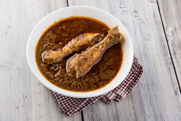 Popular caril de frango avermelhado ou masala, com um pedaço de perna proeminente, servido em uma tigela