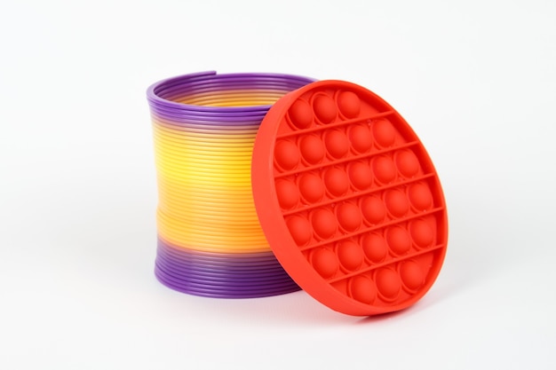 Popular juguete Slinky de plástico y Red Fidget Toys Popit sobre el fondo blanco.