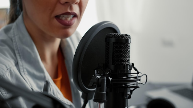 Foto el popular presentador de programas de radio en vivo por internet habla con el público en el micrófono. influenciador famoso de las redes sociales grabando una entrevista remota de podcast mientras estaba sentado en el estudio de la sala de estar. de cerca