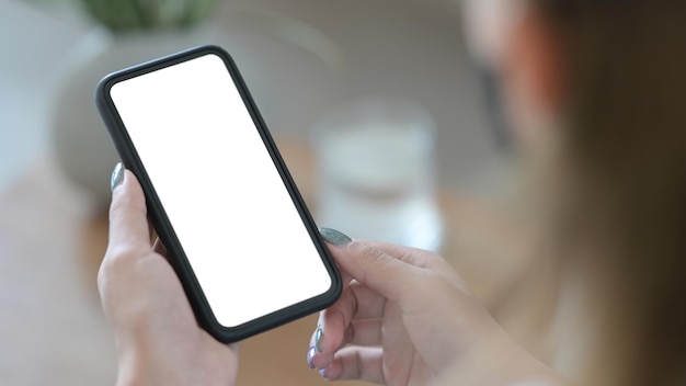 Por cima do ombro, vista de perto, mulher usando telefone inteligente Tela em branco para texto